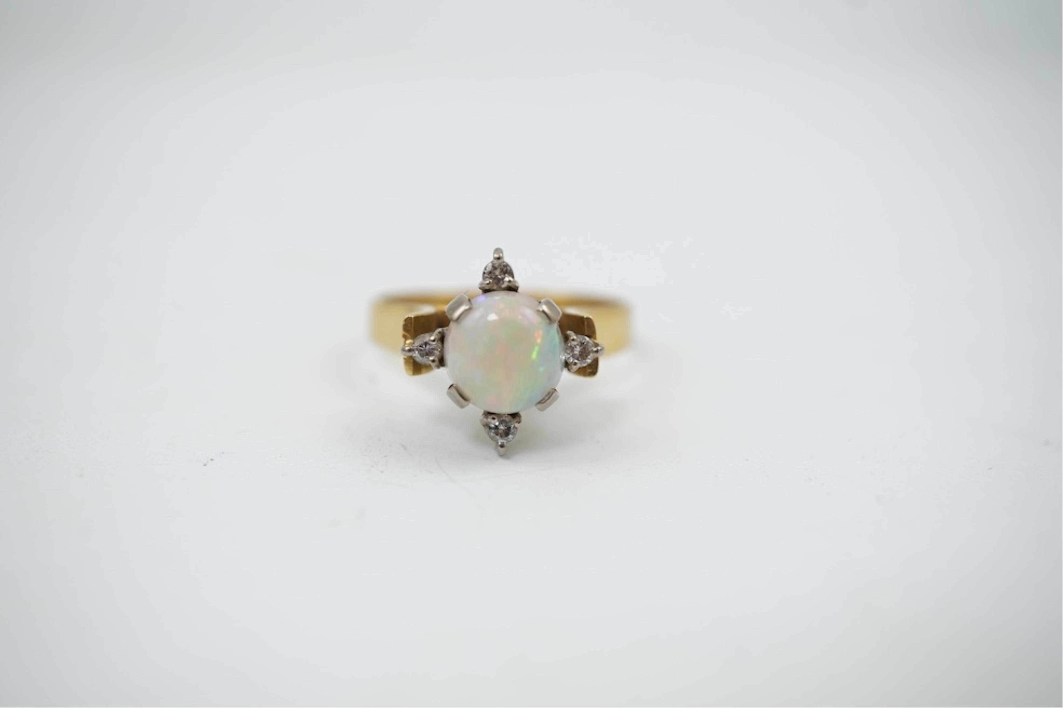 A yellow metal (stamped 18), single stone white opal and four stone diamond chip set ring, size P/Q, gross weight 3.8 grams.
